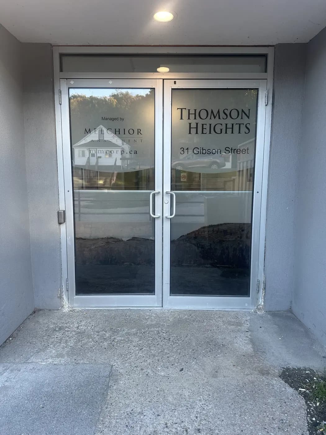 Two glass front doors with the words Thomson Heights, 31 Gibson Street.